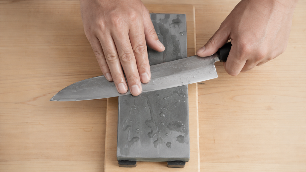 Hands sharpening a Japanese knife on a whetstone