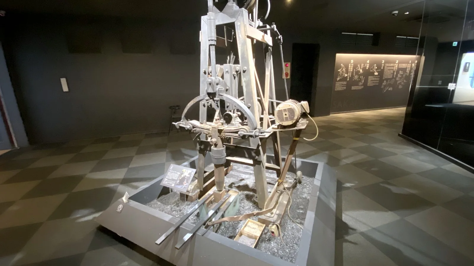A belt hammer used for forging knives, displayed on a bed of forge scale in the museum