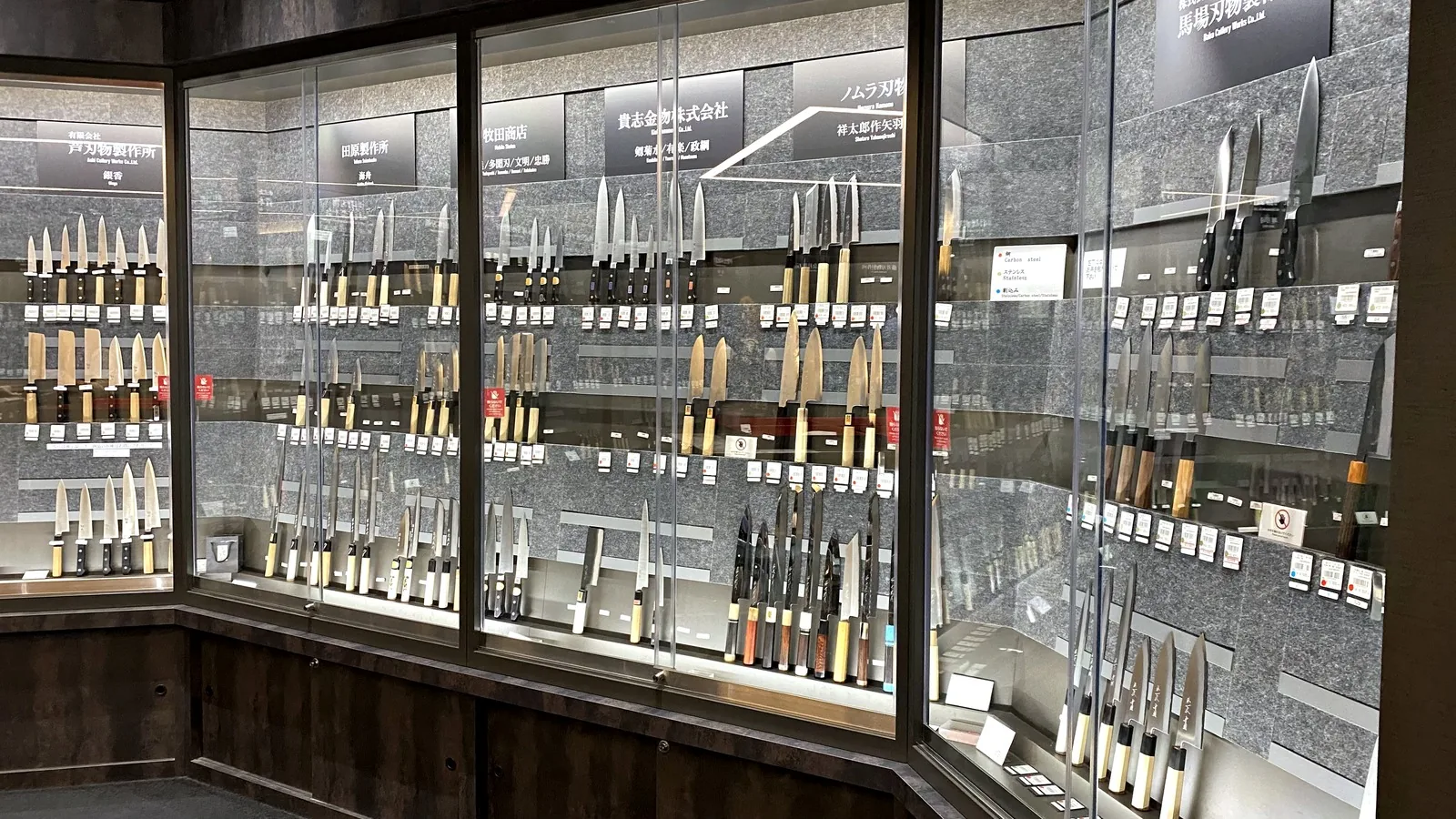 Glass cases of kitchen knives from Sakai makers arranged by maker in the building's knife shop