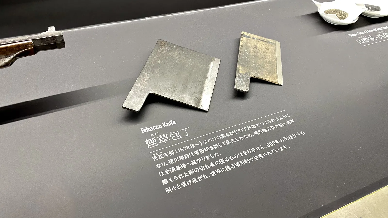 Two old tobacco-cutting knives displayed with a Japanese explanation panel