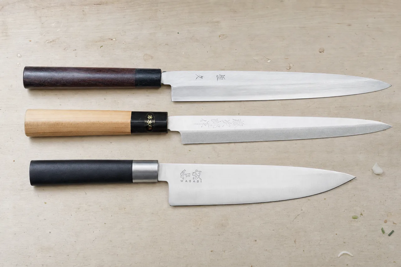 Two yanagiba sashimi knives, Tsunehisa and Tojiro, above a Kai Wasabi gyuto on a wooden counter