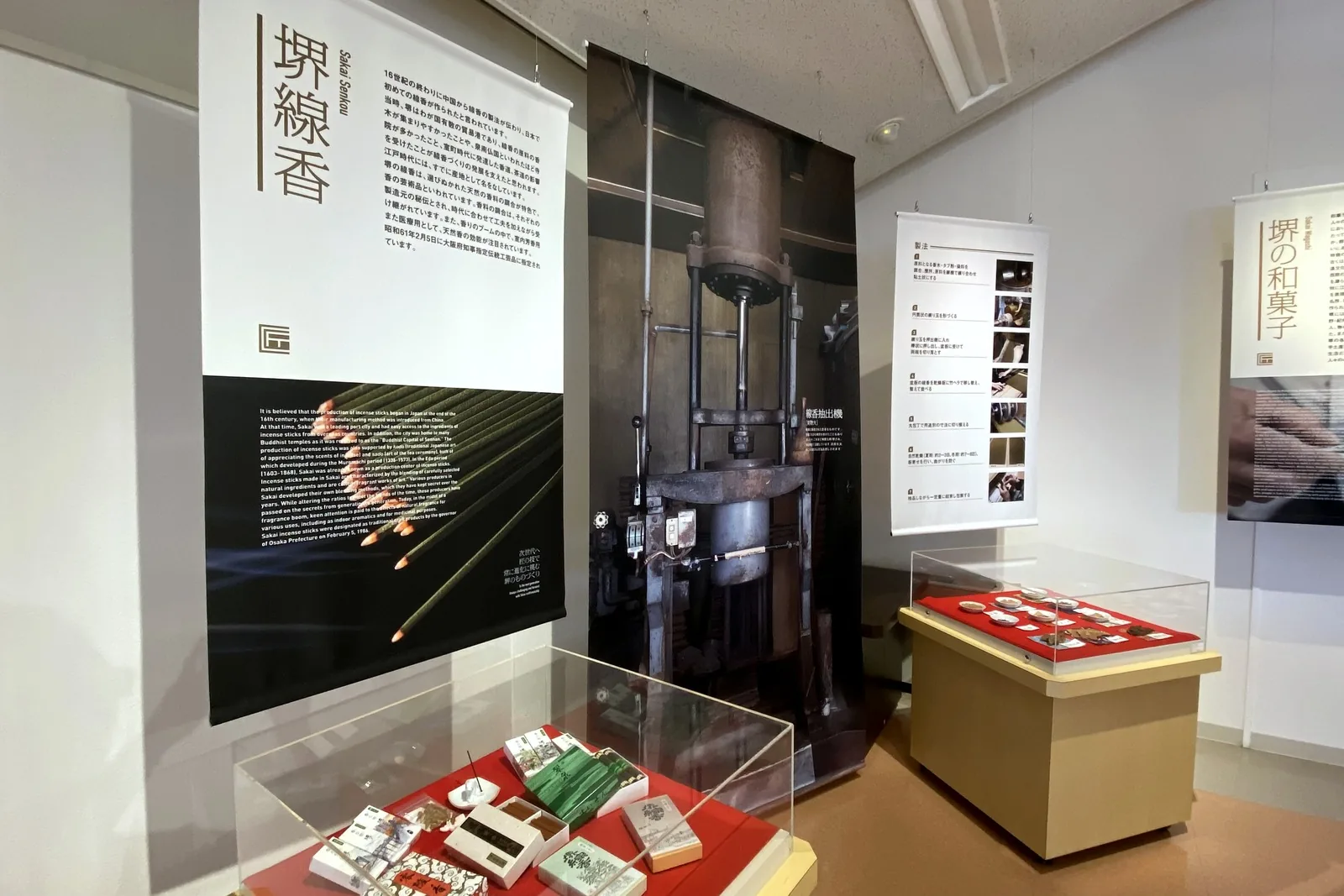 Exhibition room with a banner for Sakai incense and glass cases of incense products