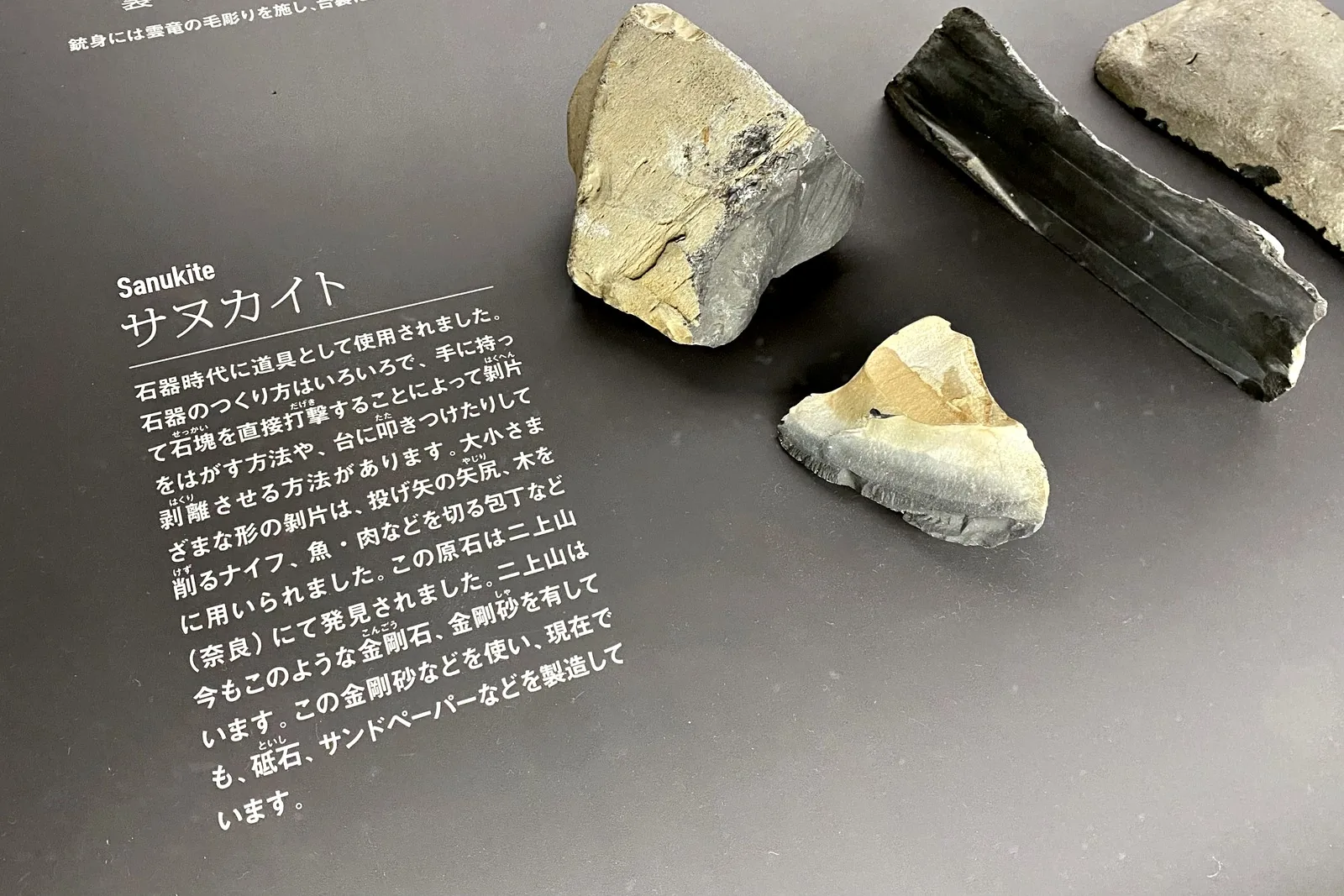 Pieces of sanukite stone displayed with a Japanese explanation at Sakai Knife Museum CUT